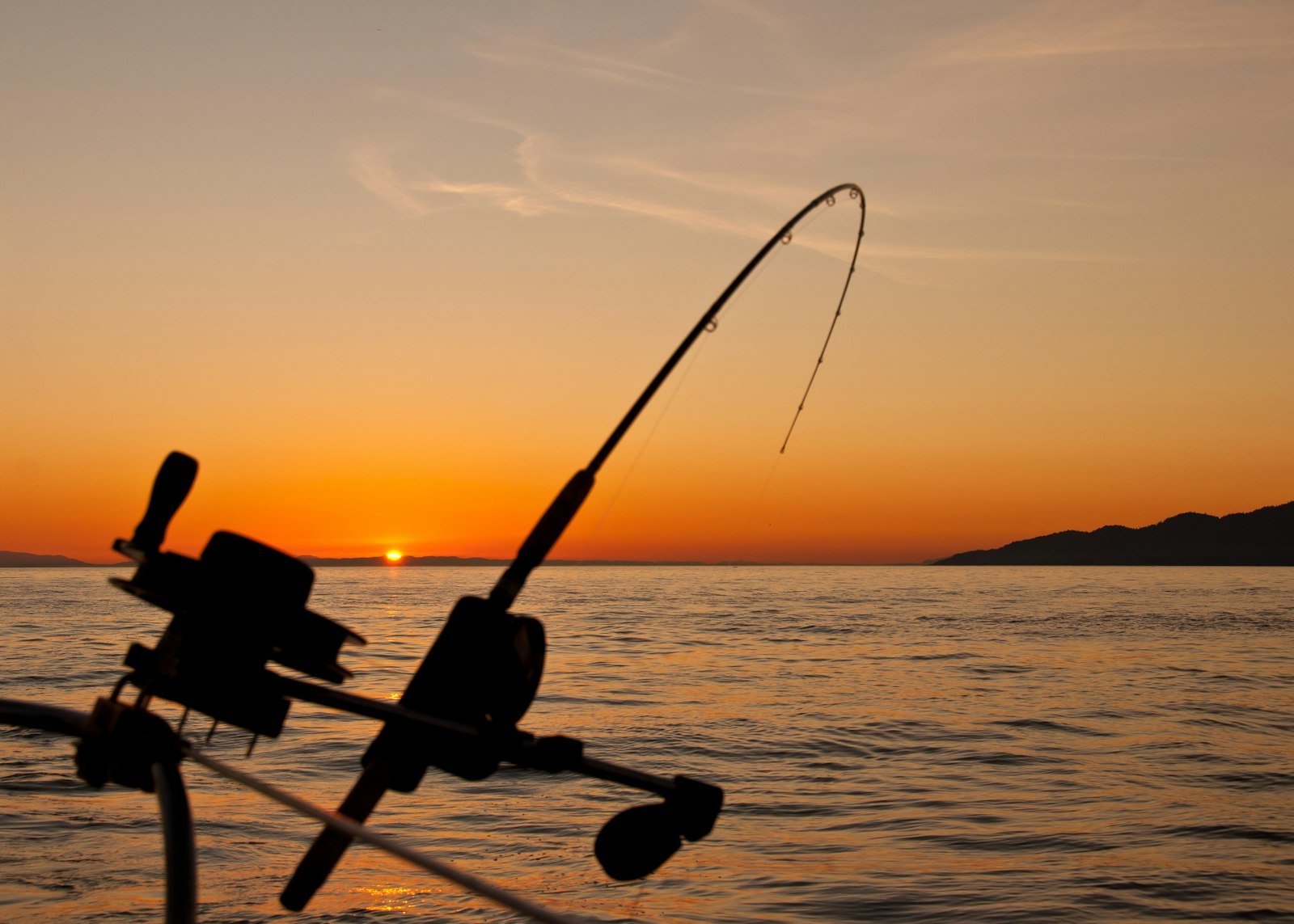 Fishing rod at golden hour over calm water